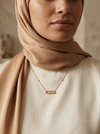Femme portant le collier Éclat Mouvant sur tenue crème et hijab beige